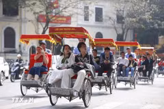 Les touristes expérimentent le voyage en cyclo autour du lac Hoan Kiem. Photo: VNA