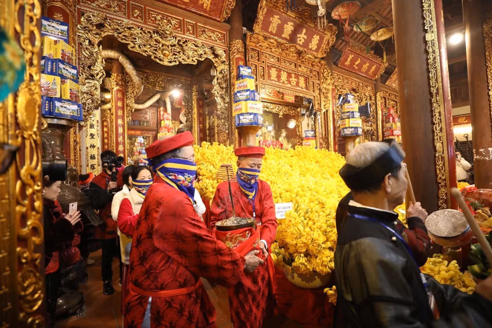 Dans une atmosphère de respect et de recueillement, des personnes chargées des rituels retirent délicatement le bol d'encens de l'autel du temple de Ky Cung. Photo: VNA