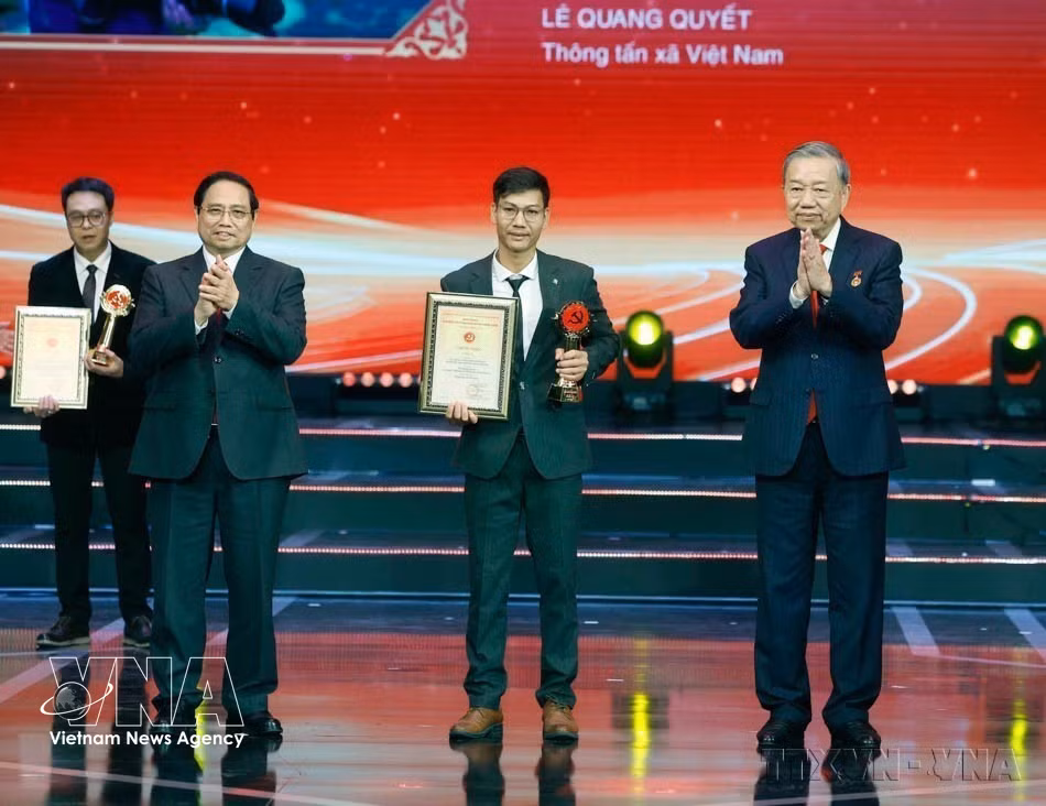 Le secrétaire général du Parti, To Lam et le Premier ministre Pham Minh Chinh remettent le Prix A au journaliste Le Quang Quyet, de l’Agence vietnamienne d’information, lors de la cérémonie de remise du 10ᵉ Prix national du Marteau et de la Faucille d’or, le 3 février 2026 à Hanoï. Photo: VNA
