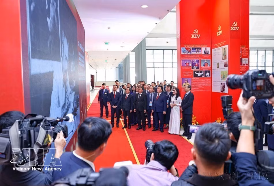 Le permanent du Secrétariat du Comité central du Parti, Tran Cam Tu et d'autres dirigeants du Parti et de l’État visitent l’exposition photographique "Sous le drapeau du Parti – Le pays entre dans une nouvelle ère", réalisée par la VNA, lors de l’inauguration du Centre de presse du 14e Congrès national du Parti, le 14 janvier 2026. Photo: VNA