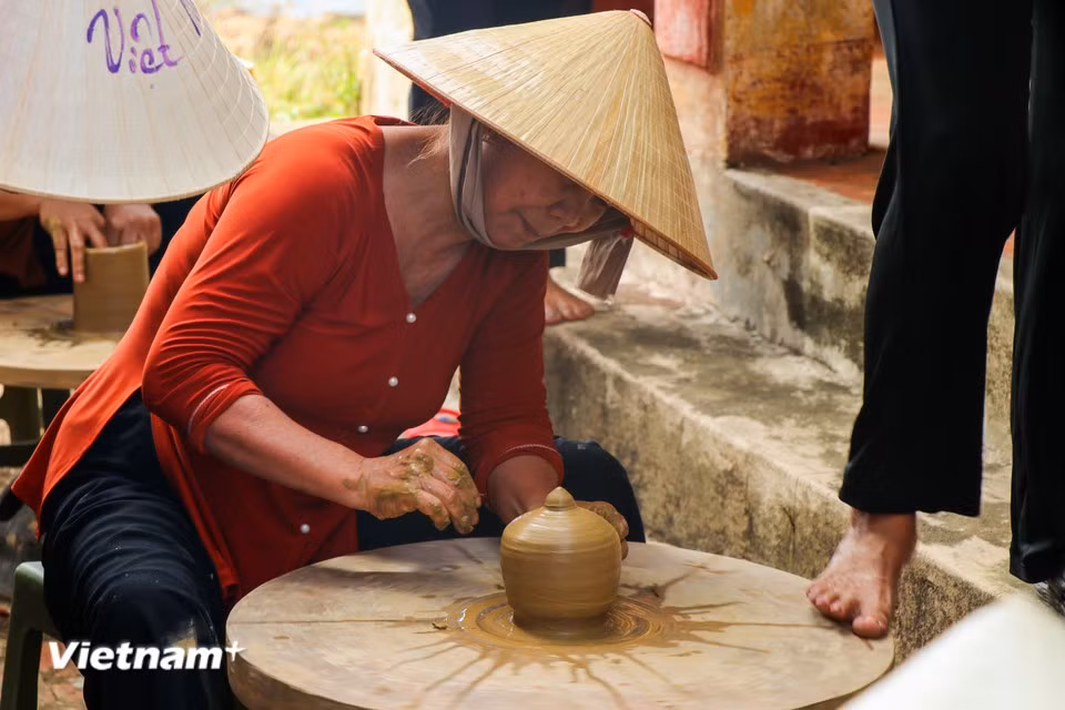 Une artisane modèle une pièce de céramique sur un tour traditionnel, dont la rotation est rythmée et contrôlée par la force des pieds. Photo : Vietnam+