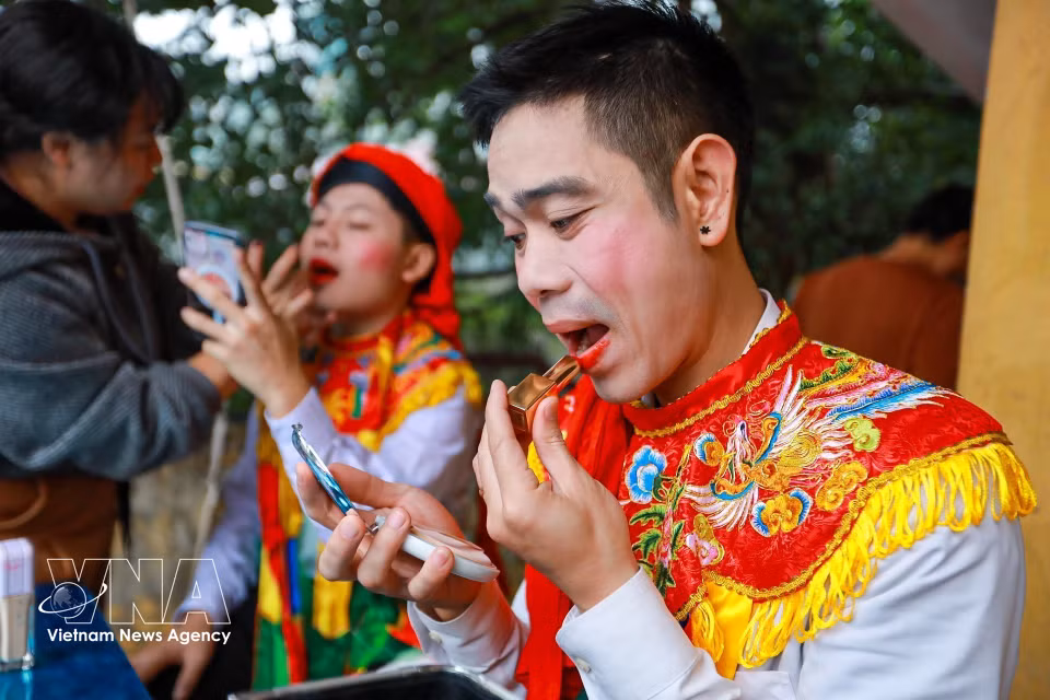 Dans les coulisses, les interprètes s’affairent avec soin, ajustant minutieusement leur maquillage et leurs costumes féminins avant le début de la cérémonie. Photo : VNA
