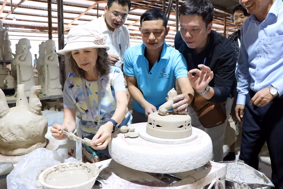 Les invités internationaux découvrent le processus de production de la céramique Chu Dâu. Chaque produit subit un processus rigoureux en cinq étapes : préparation de l'argile, façonnage, décoration des motifs, émaillage et cuisson. Photo : Manh Tu – VNA
