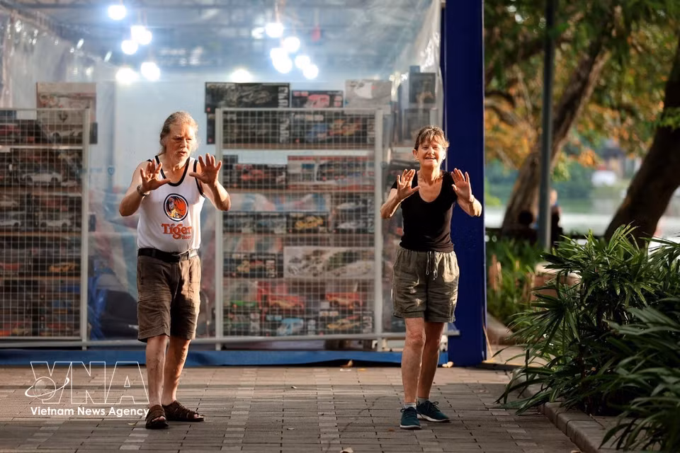 Des touristes étrangers du troisième âge séjournant au Vietnam débutent leur journée par une séance d'activité physique matinale. Photo : VNA