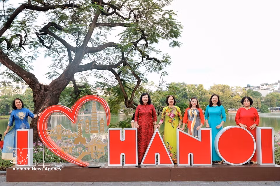 Vêtues de la traditionnelle tunique "ao dai", des femmes âgées immortalisent la sérénité d'une matinée d'automne à Hanoï. Photo : VNA