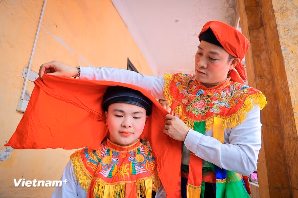 Dans les coulisses, les interprètes s’affairent avec soin, ajustant minutieusement leur maquillage et leurs costumes féminins avant le début de la cérémonie. Photo : VNA