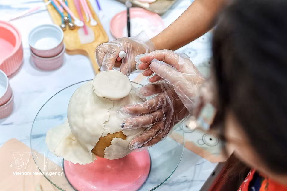 L’artisane lisse et ajuste avec soin la couche extérieure de la pâte pour parfaire la silhouette du vase avant l’intégration des éléments décoratifs. Photo : VNA