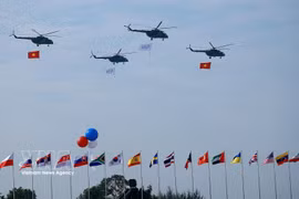 Un vol de formation d’hélicoptères arborant le drapeau national vietnamien effectue une démonstration aérienne lors de la cérémonie d’ouverture de l’Exposition internationale de défense du Vietnam 2024. Photo : VNA