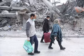 Des personnes marchent à travers les décombres après des attaques. Photo: Xinhua/VNA