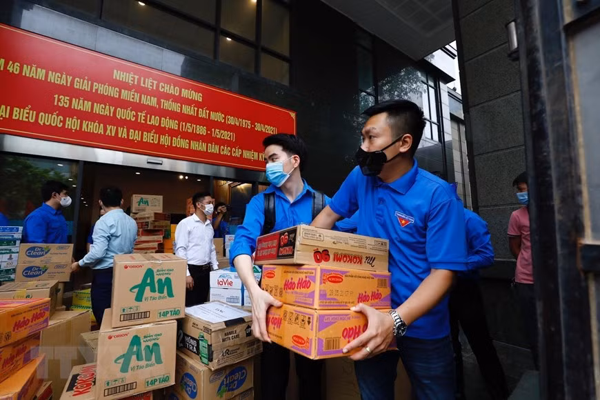 Des membres de l’antenne de l’Union de la jeunesse communiste Ho Chi Minh au sein du bloc des organes du ressort central transportent des biens de première nécessité pour soutenir la province de Bac Giang impactée par le COVID-19. Photo: VNA