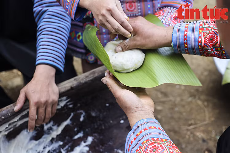 Les femmes prennent la relève. Tout d’abord, elles façonnent le gâteau en cercle, puis l’enveloppent de feuilles de bananier chauffées au feu. Ensuite, elles pressent doucement le gâteau avec leurs mains pour créer une forme ronde comme la lune et le soleil. Photo: VNA