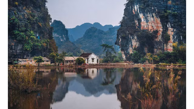 De petites maisons construites au bord d’un lac dans la province de Ninh Binh.