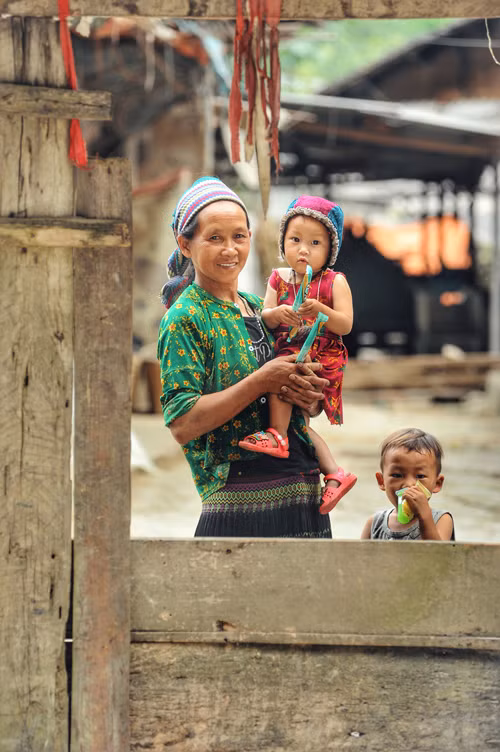 Des enfants et leur grand-mère devant leur maison dans la commune de Pho Cao.
