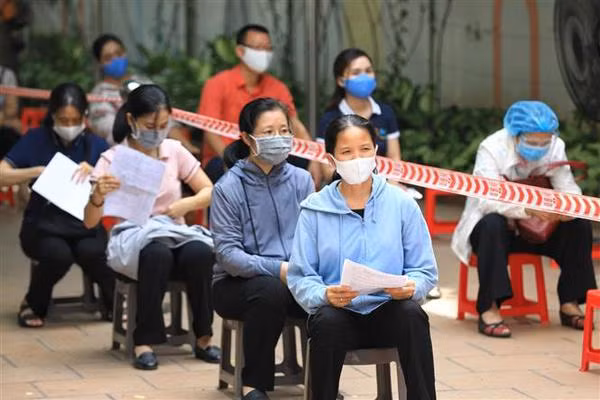 Les habitants de l’arrondissement de Hoan Kiêm respectent la garantie de la distance aux points de vaccination. Photo : VNA