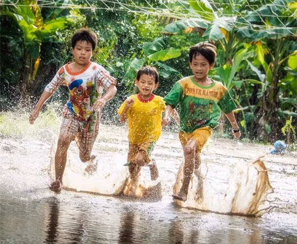 Enfants jouant sur une route inondée à Tay Ninh