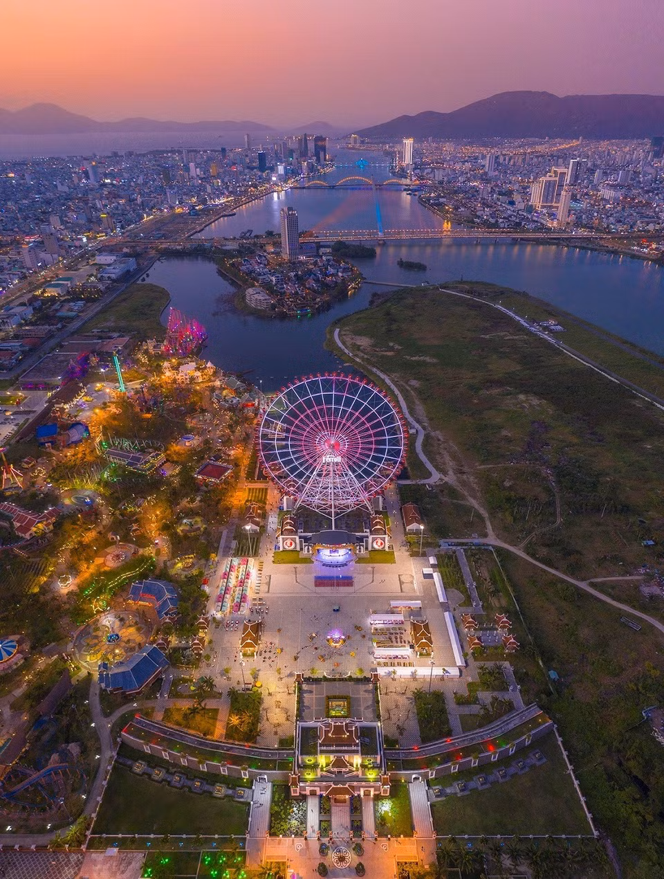 La photo offre une vue panoramique de la ville de Da Nang au coucher du soleil, à l'Asia Park, avec au loin les ponts enjambant la rivière Han. Photo: VNA