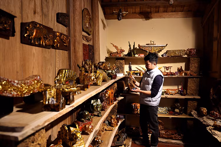 Le peintre-artisan Nguyên Tân Phat et ses œuvres. Photo : VNA