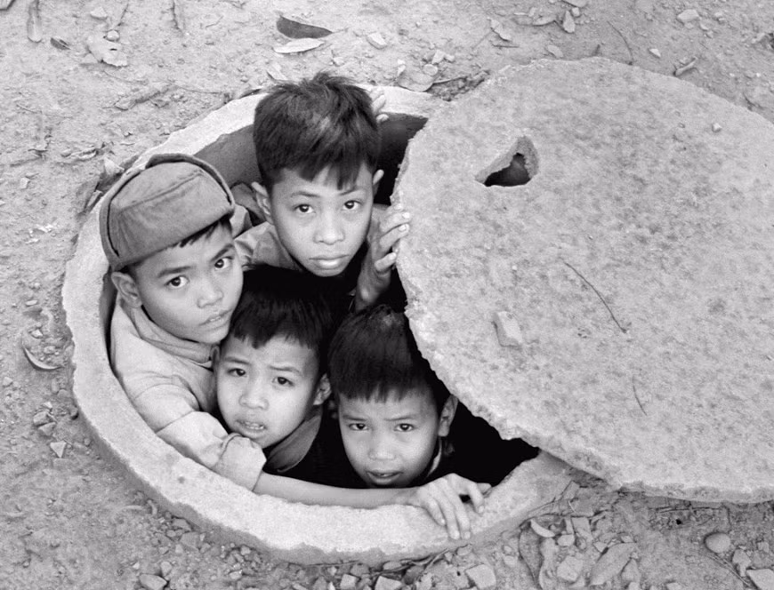 Des enfants lèvent les yeux de l'intérieur d'un abri anti-bombes devant l'hôtel Metropole de Hanoï en 1968. Des abris souterrains ont été installés à de nombreux endroits de la capitale au cours de la période 1965-1972. Ces bunkers ont été construits sur les deux trottoirs des rues principales pour aider les résidents à s'abriter les bombes le plus rapidement possible. Environ 130 photos sur Hanoï de 1967 à 1975, prises par Billhardt, sont présentées lors d'une exposition au Manzi Exhibition Space (14 rue Phan Huy Ich) et au Manzi Art Space (2 ruelle Hàng Bún) dans la capitale, du 3 octobre au 15 novembre 2020. Photo: Vietnamplus