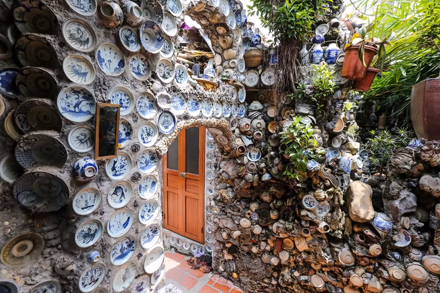 Sur les murs de sa maison, on peut trouver un gouvernail de bateau à voile, des bouteilles, des centaines d'assiettes et de bols.