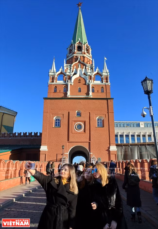 Les touristes posent pour photos souvenirs devant la tour Troitskaya de Kremlin. 