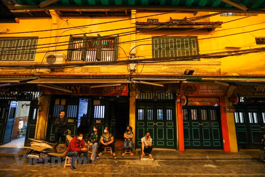  La fermeture temporaire des commerces est nécessaire pour prévenir la propagation du Covid-19. Certains gens portent des masque de protection devant leur maison et restaurant. L’ambiance est des plus calmes. Un habitant local a partagé : "Jamais je n'ai vu la rue Ta Hiên aussi calme ! C'est un spectacle rare car la zone est connue sous le nom de +rue qui ne dort jamais+". Tout le monde fait contre mauvaise fortune bon cœur car cette situation, bien évidement, n’est que temporaire. Tout devrait rentrer normalement dans l’ordre dans les semaines à venir en vue de reprendre leurs acivités professionnelles. Photo: VietnamPlus 