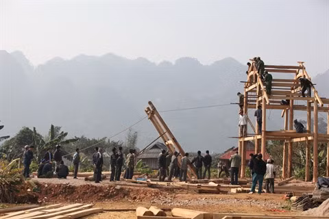Une trentaine de jeunes villageois participent à la construction d’une maison sur pilotis.