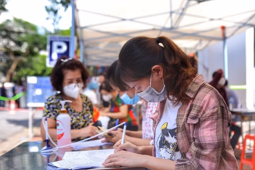 Des habitants du quartier de Pham Dinh Hô, arrondissement de Hai Ba Trung, font leur déclaration de l'état de santé avant la vaccination. Photo : VNA