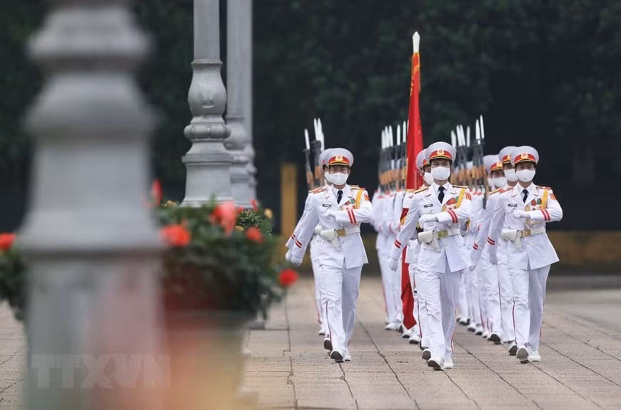 Des gardes du mausolée du Président Hô Chi Minh défilent avec le drapeau national. Photo: VNA