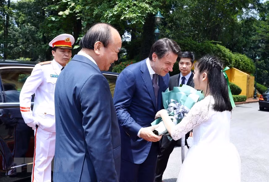 Le Premier ministre italien reçoit un bouquet de fleurs de bienvenue. 