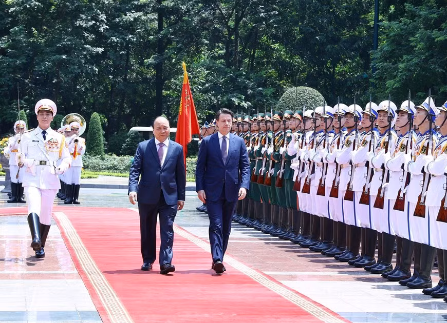 Le Premier ministre Nguyên Xuân Phuc (gauche) et le Premier ministre Giuseppe Conte passent en revue la garde d'honneur.