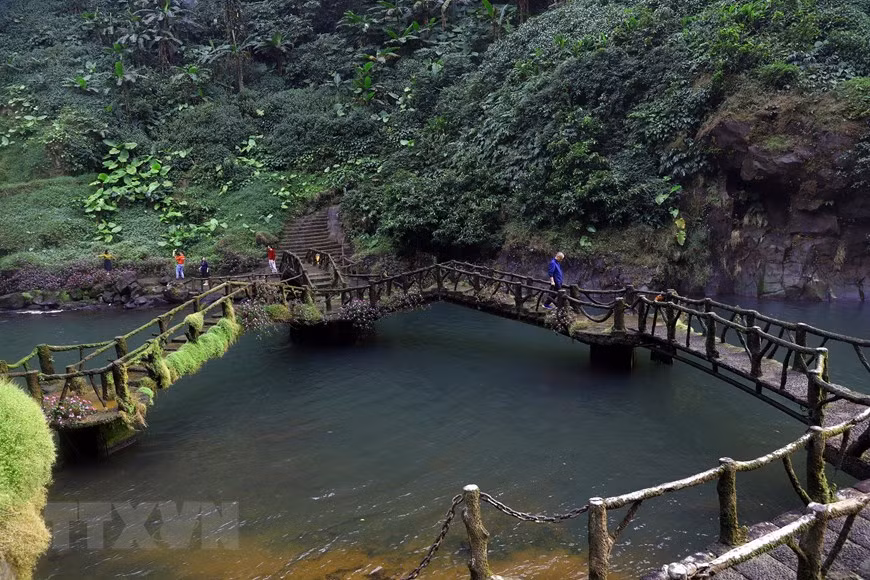 Le petit pont relie les deux rives au pied de la cascade. Photo : VNA