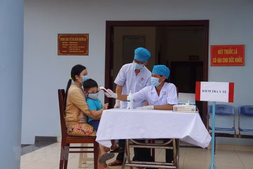 Des médecins militaires du centre médical du bourg de Truong Sa contrôlent la santé d'un enfant et indique à sa mère des mesures préventives. Photo: VNA