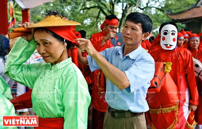 L'artisan aide une artiste à préparer des costumes avant de présenter la danse Ngo Quoc lors du festival Lam Kinh 2018. 