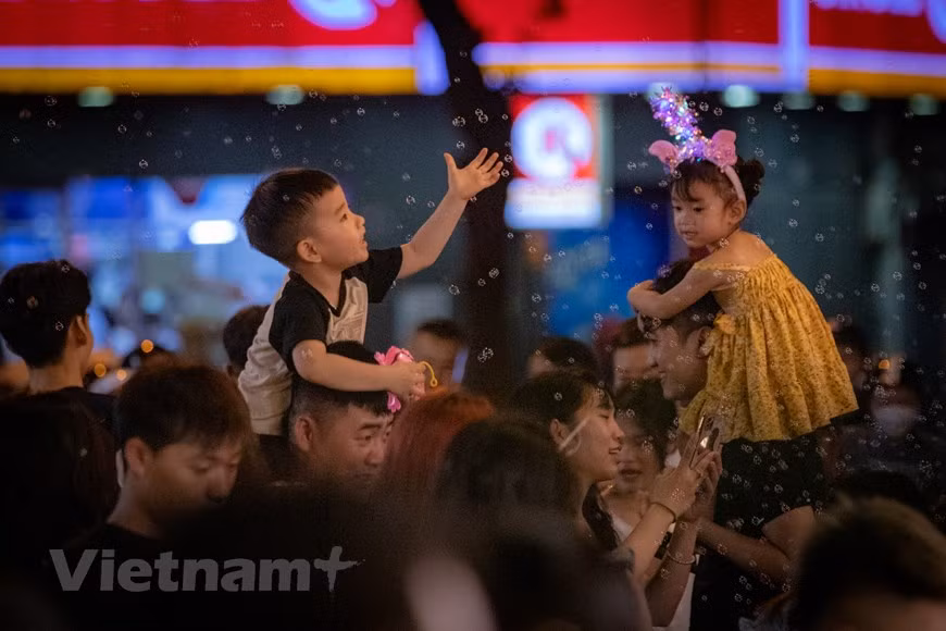 Les enfants sont contents de sortir avec leurs parents et de découvrir l'atmosphère de la Fête de la mi-automne dans la rue Hang Ma.