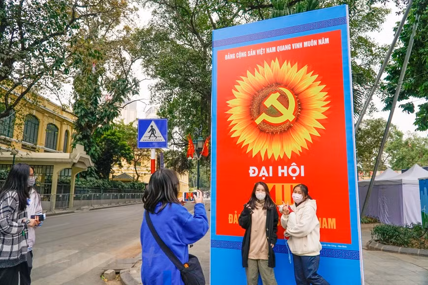 Les jeunes aiment prendre des photos devant de grandes affiches. Photo: Vietnam+