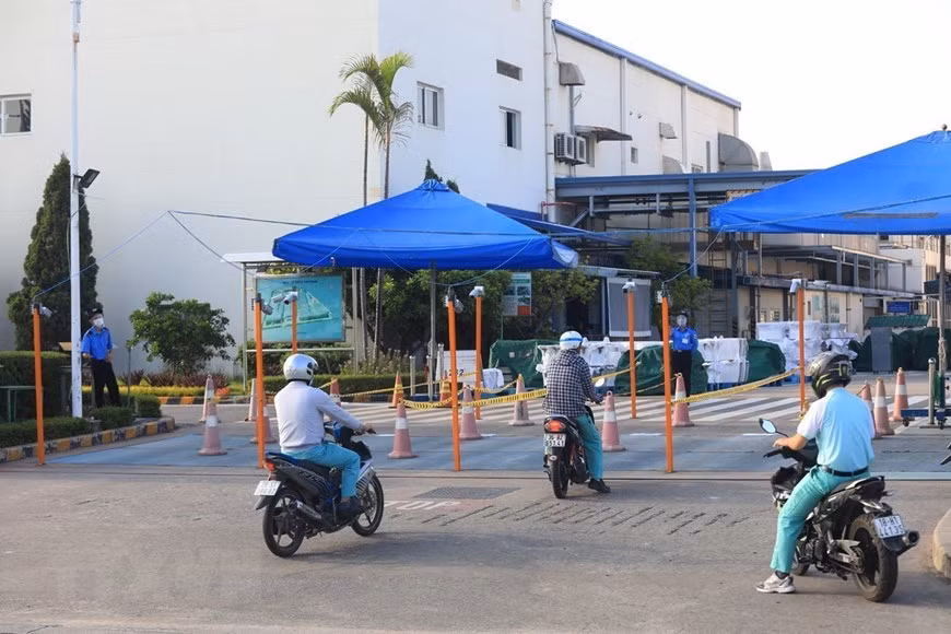 Les travailleurs venant travailler à la société TOTO Vietnam, dans la zone industrielle de Thang Long à Hanoï, doivent suivre des voies séparées. Photo: VNA