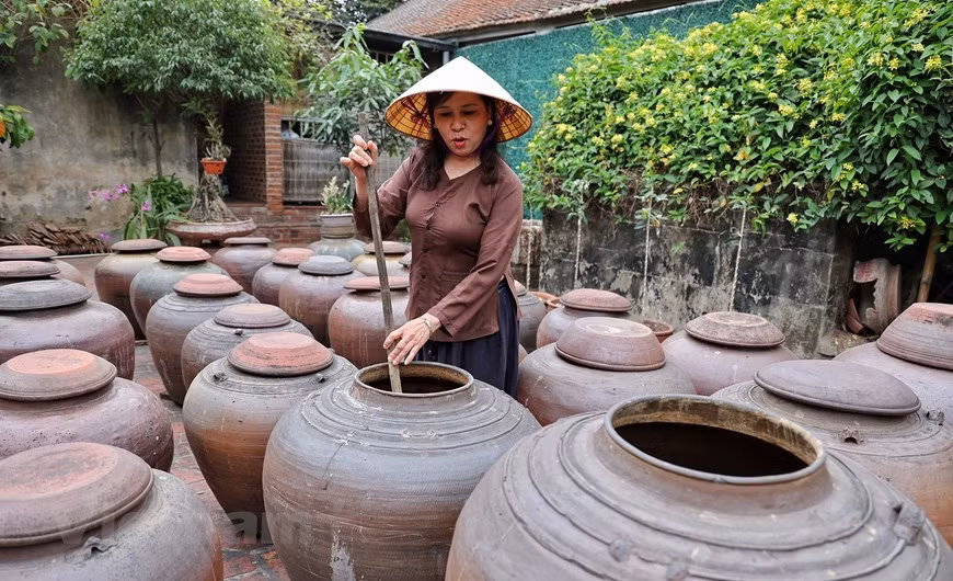 Chaque jarre contient jusqu'à des centaines de litres de sauce soja, un souvenir indispensable une fois que les visiteurs viennent à Duong Lam. Plus la sauce est conservée longtemps, plus elle sera délicieuse. En visitant les maisons anciennes de Duong Lam, les visiteurs peuvent acheter cette pâte salée à base de soja fermenté comme cadeau. Des jarres en terre cuite contenant des sauces soja bordent les cours, exhalant doucement un parfum caractéristique de sarriette et de noisette. Les valeurs culturelles traditionnelles, un paysage et une architecture typiques de la campagne du delta du fleuve Rouge et diverses spécialités ont fait du village de Duong Lam une destination touristique idéale. Photo: Vietnamplus