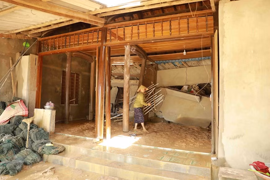 Une femme se prépare pour fuir la maison endommagée par un glissement de terrain. Photo: VNA