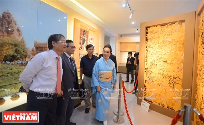 Toba Mika présente ses œuvres au vice-président du Comité populaire municipal de Da Nang, Nguyen Ngoc Tuan (chemise blanche), et au consul général du Japon à Ho Chi Minh-Ville, Kawaue Junichi (veste).