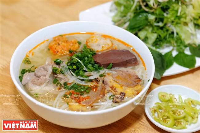 La soupe est servie avec du basilic, de minces tranches de fleur de bananier, des quartiers de citron et des piments verts.