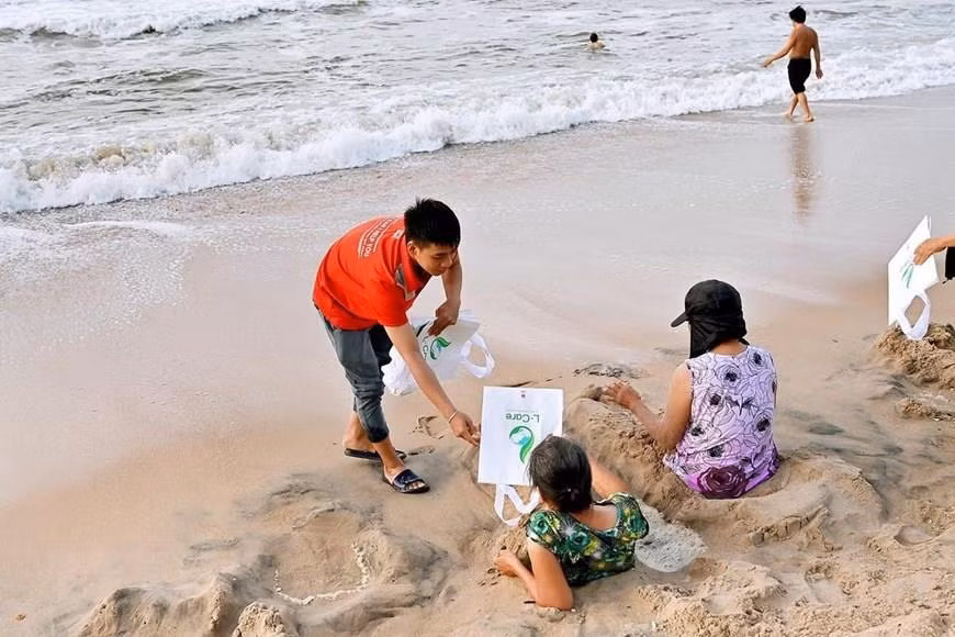 Des volontaires offrent des sacs respectueux de l'environnement aux habitants à la plage de Dôi Duong. Photo: VNA 