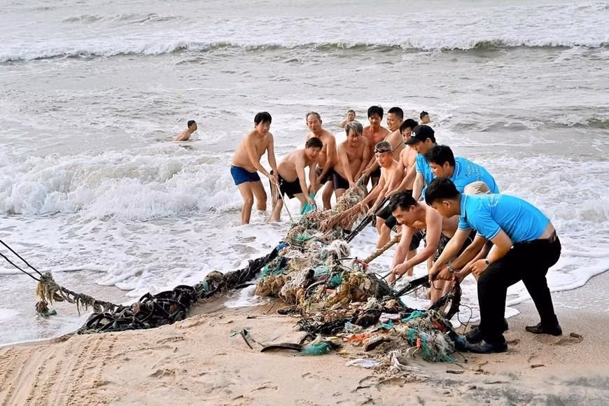 Des habitants et des volontaires ramassent des déchets à la plage de Dôi Duong. Photo: VNA 