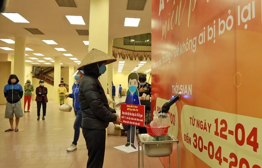 Des personnes défavorisée reçoivent le riz à partir d'un ATM installé à la commune de Phuc Diên, district de Bac Tu Liêm à Hanoi. Photo: VNA 