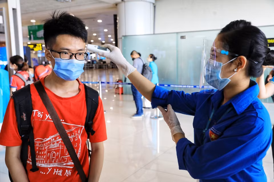 Le personnel de l'aéroport de Noi Bai vérifie la température corporelle pour 350 étudiants et professeurs de l'Université de Médecine de Hanoï avant l'heure d'embarquement. Photo: VNA