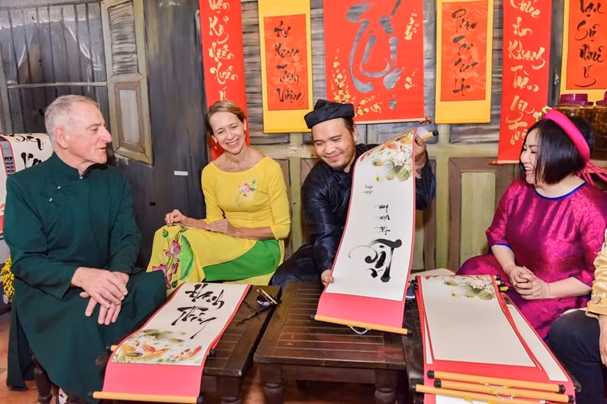 Les invités étrangers apprécient la calligraphie vietnamienne. A l’occasion du Têt traditionnel, les Vietnamiens ont coutume de se rendre chez un maître calligraphe pour retranscrire en idéogrammes leurs souhaits de bonheur, de santé, de fortune et de longévité pour une nouvelle année. Ils trempent leurs gros pinceaux dans un écritoire d’encre de Chine pour écrire les caractères «Bonheur», «Longévité», «Génie», sur de grands carrés de papier rouge..., ou des vœux de prospérité sur de longs rectangles de papier parallèle. La calligraphe exige une connaissance parfaite de son matériel. Aucune retouche n’est possible. D’où l’importance de la préparation psychologique et même des effets de mise en scène qui l’accompagnent parfois. C’est la vigueur du coup de pinceau qui compte. Bien plus qu’une technique de peinture, c’est le perfectionnement moral et culturel que le calligraphe cherche à atteindre. Photo: Vietnam+