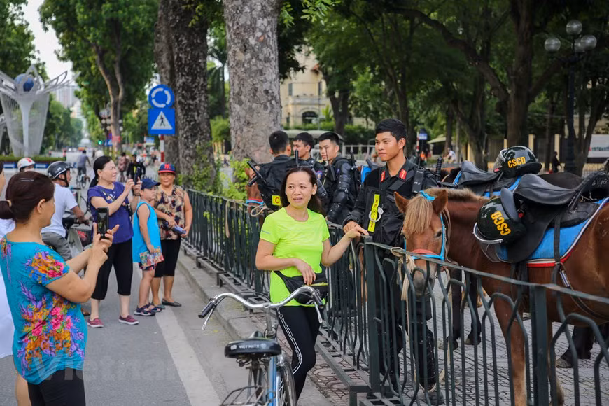 Dès la bonne matinée du 8 juin, de nombreux habitants de la capitale se sont très enthousiastes de voir de leur propres yeux des chevaux de la Police mobile à cheval. Ils se sont précipités et se sont approchés des ces chevaux pour prendre des photos avec eux. Pour préparer à ce défilé, la force de la police mobile à cheval doit être présente très tôt au bâtiment près de la l’Assemblée nationale pour accomplir les derniers préparatifs. Plus de 60 chevaux ont été soignés et domestiqués par la Police mobile à cheval, relevant du commandement de la police mobile, du ministère de la Sécurité publique du pays. Photo : Minh Son/VietnamPlus 