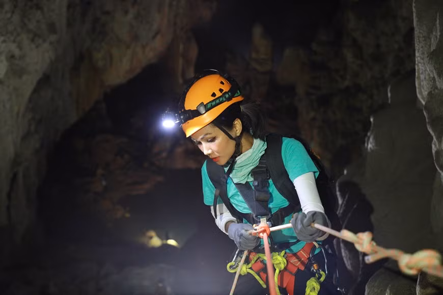 En raison de la face visqueuse de la falaise, H’Hen Nie est tombée brusquement et a heurté un rocher après avoir grimpé sur une courte distance. Cependant, elle n'a souffert que de petites rayures grâce à la protection de son uniforme et a été immédiatement assistée. Lors de la première journée de son parcours à la conquête de la grotte Son Doong, la plus grande caverne de la planète située dans le parc national de Phong Nha - Ke Bang, dans la province centrale de Quang Binh, la Miss H hen Niê et sa suite passent une nuit dans la grotte En. Photo : Hai An/Vietnam+ 