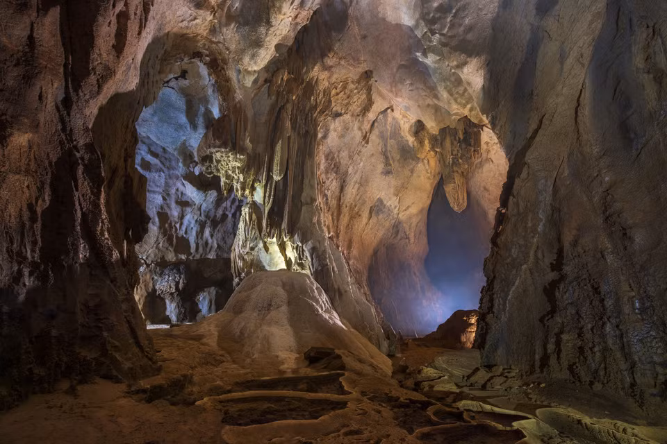 L'entrée de la grotte est assez grande et descend en pente. Les touristes sont équipés d'équipements pour assurer leur sécurité.