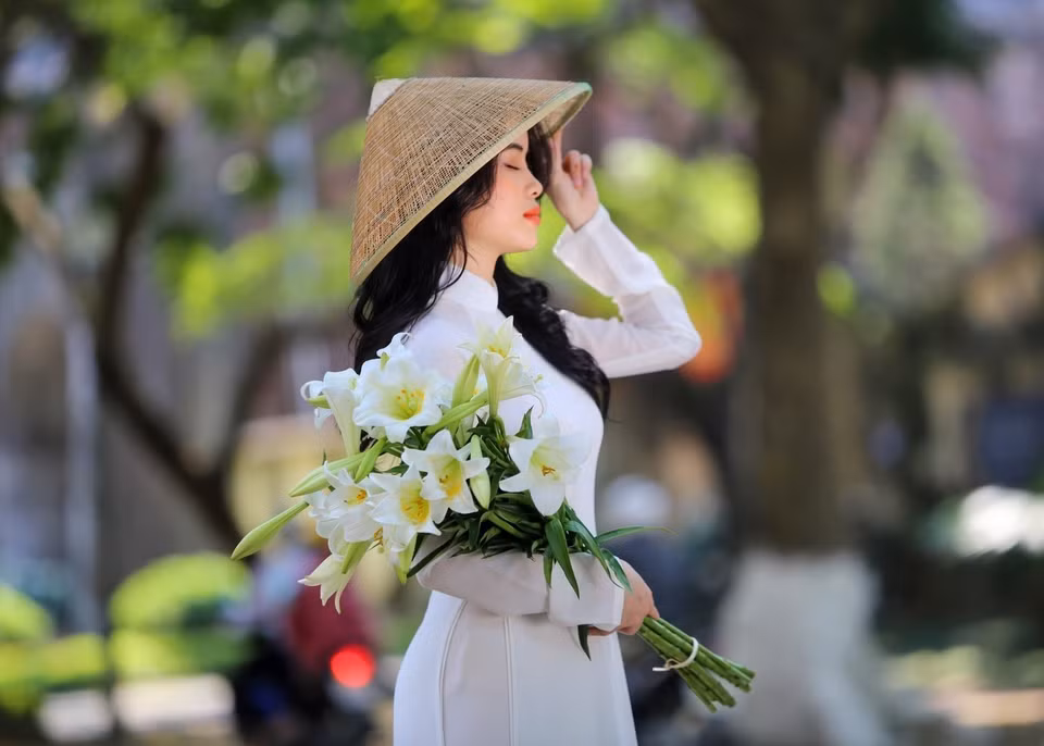 Photo en ao dai avec des lys de Pâques. 