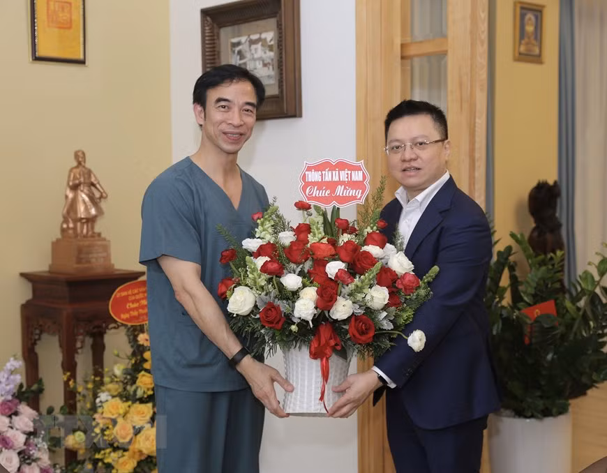 Le Quoc Minh, membre du Comité central du Parti, secrétaire du Comité du Parti de la VNA, directeur général adjoint de la VNA, offre des fleurs au directeur de l'hôpital de Bach Mai, Nguyen Quang Tuan. Photo: VNA